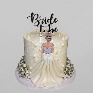 White bridal shower cake with 3D fondant dress skirt and edible pearls. Custom bride to be cake available for delivery in Hyderabad, Banjara Hills, and Jubilee Hills.