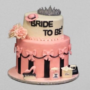 2-tier pink and white fashion theme cake featuring edible Chanel and Dior shopping bags, a silver tiara, and black stripes. Custom bride to be cake delivery in Hyderabad, Banjara Hills, and Jubilee Hills.