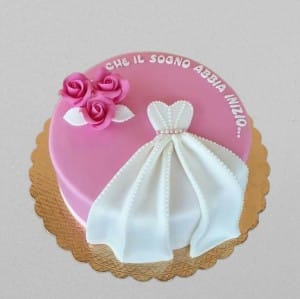 Pink round cake with white 3D fondant wedding dress draping over the side and pink roses. Custom bridal shower cake available in Hyderabad, Banjara Hills, and Jubilee Hills.