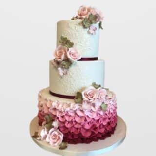 3-tier vintage engagement cake with white lace detailing, pink to magenta ombre ruffles, and sugar roses. Custom wedding cake delivery in Hyderabad, Banjara Hills, and Jubilee Hills.