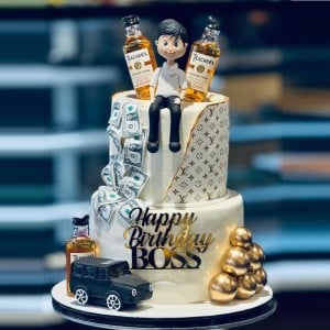 2-tier luxury birthday cake for boss with gold monogram pattern, edible money, alcohol bottles, and 3D caricature. Custom corporate cake delivery in Hyderabad, Hitech City, and Madhapur.